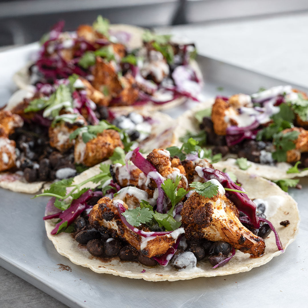 Crispy Cauliflower Tacos With Spiced Black Beans, Pickled Cabbage, Whipped Feta Crema, Coriander & Lime